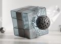 A minimalist 3D editorial graphic showing a sleek glass and metal cube being fractured by a heavy, metallic chain-link sphere, symbolising the impact of blockchain-enforced data rights over centralised platforms.