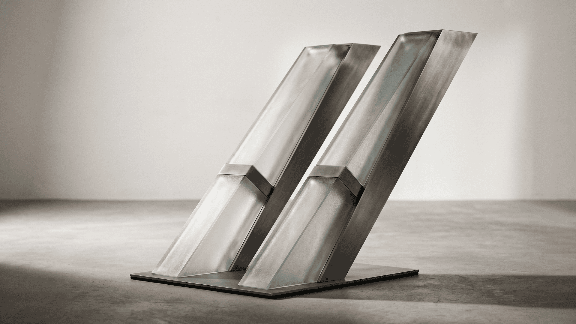 Minimalist architectural sculpture of angled frosted glass and brushed titanium pillars, symbolising OpenAI's accelerated funding round and Anthropic's IPO.